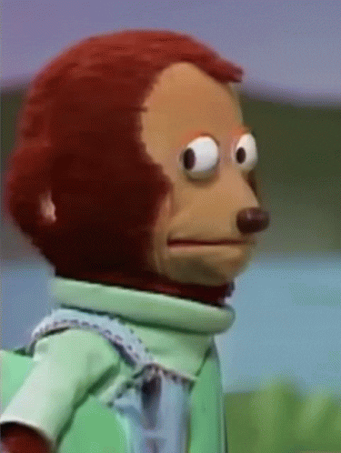 GIF of a red-haired monkey puppet in a teal shirt slowly turning its head to the side to avoid eye contact.
