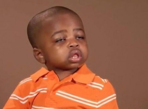Young Black child in an orange striped polo shirt, tilting his head with a tired, skeptical expression.